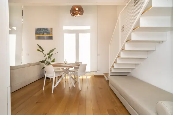 Loft Frola — zona pranzo con tavolo rotondo e scala a giorno